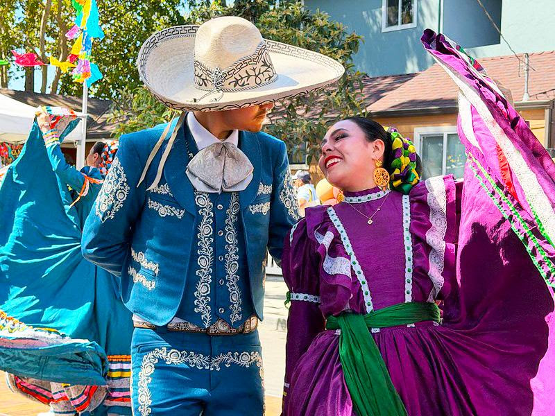 Two performers in colorful traditional Mexican attire dance together during St. Francis Center’s 40th Anniversary Block Party celebration in Redwood City.